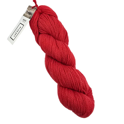 A skein of Sweater Worsted Yarn by Blue Sky Fibers in the color Barn a red yarn with a paper label attached, photographed on a clean white background.