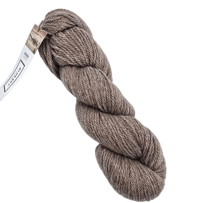 A skein of Sweater Worsted Yarn by Blue Sky Fibers in the color Chocolate Milk a taupe brown yarn with a paper label attached, photographed on a clean white background.