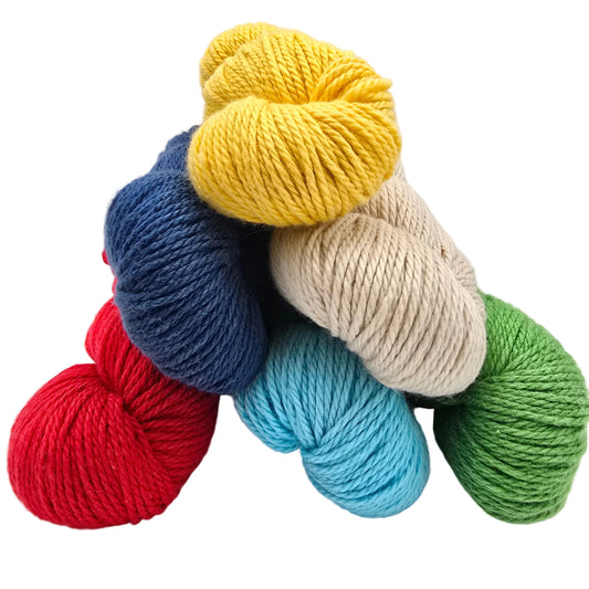 A stack of six skeins of Sweater_Worsted yarn in assorted colors including yellow, blue, beige, red, light blue, and green on a white background.