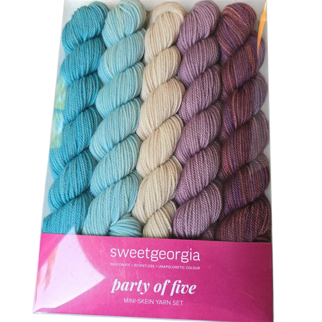 Set of five mini skeins of Sweetgeorgia brand yarn in colors blue, green, beige, and purple in SweetGeorgia pink and white packaging with label on white background.