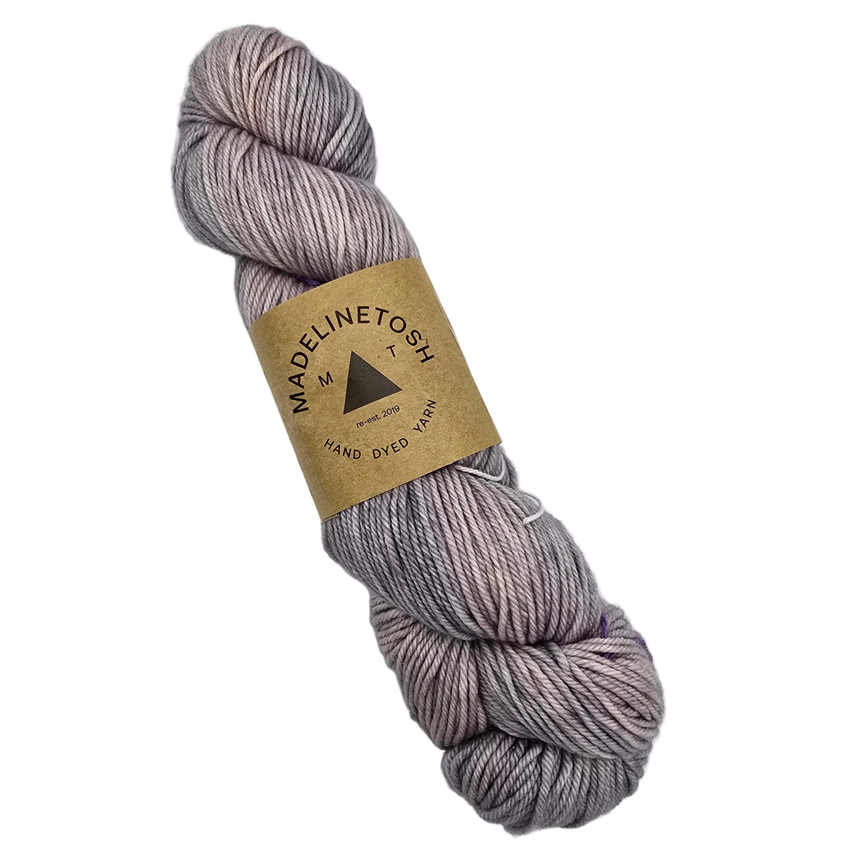 A single skein of Tosh_DK Yarn_by_Madelinetosh_in the color_Calligraphy a variegated lavendar yarn wrapped in a brown kraft paper label, shown on a plain white background.