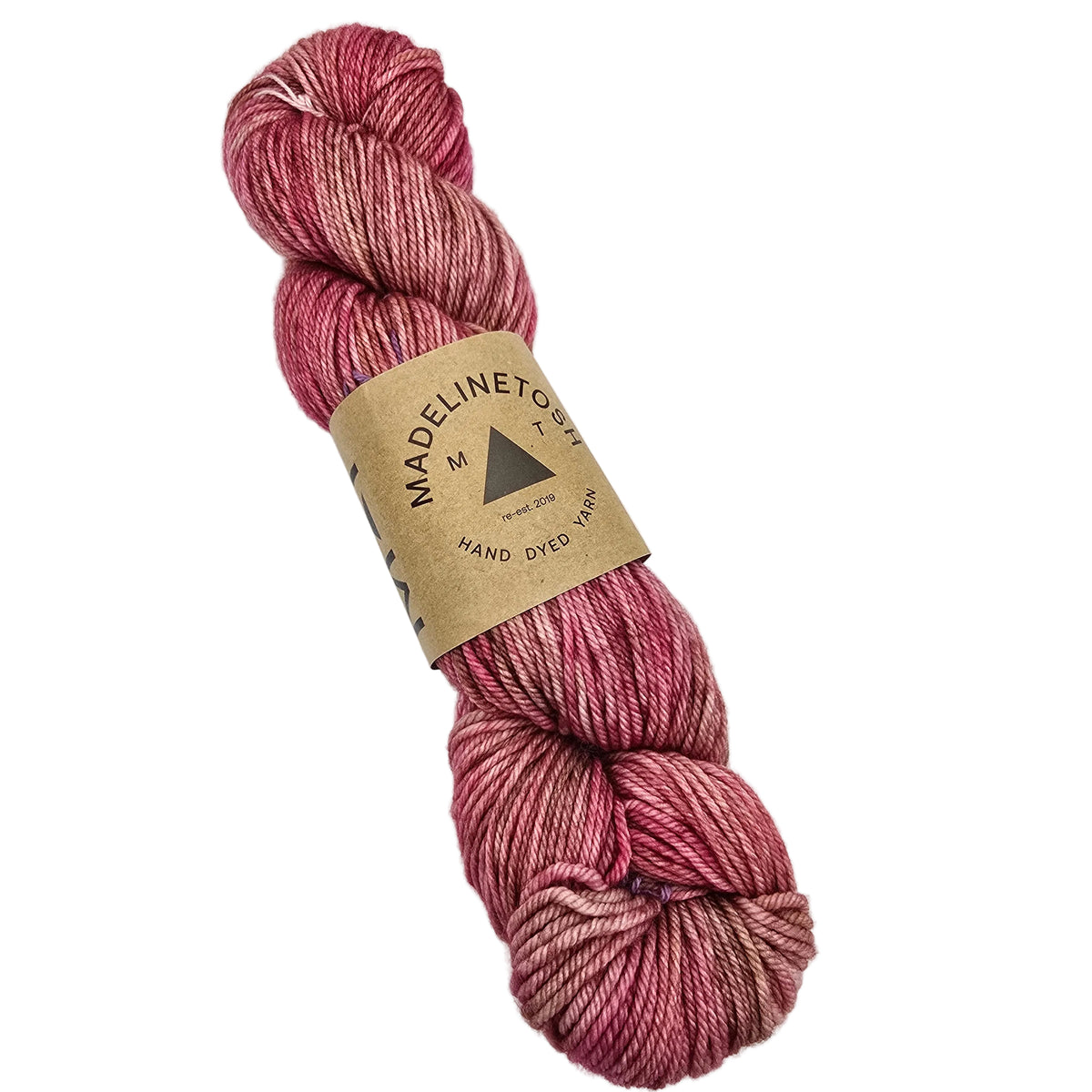 A single skein of Tosh_DK Yarn_by_Madelinetosh_in the color_Fragrant a variegated pink yarn wrapped in a brown kraft paper label, shown on a plain white background.