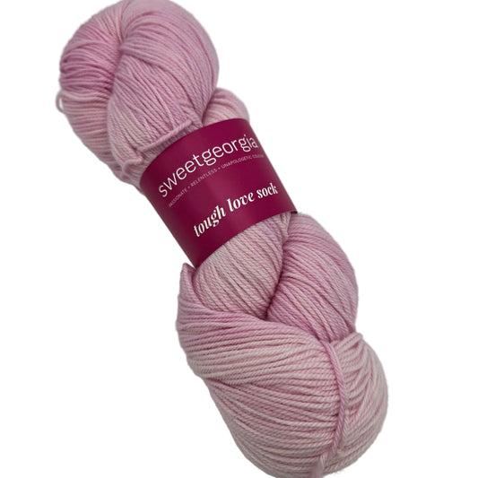 Image of a single skein of Tough Love Sock by SweetGeorgia Yarns in the color Candy Floss with label on a white background.