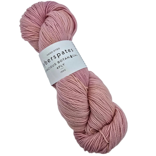 A skein of hand-dyed Vivacious_Botanicals_4ply yarn_by_Fyberspates_in the color Peach_Melba a dusty pink shade with label on a white background.