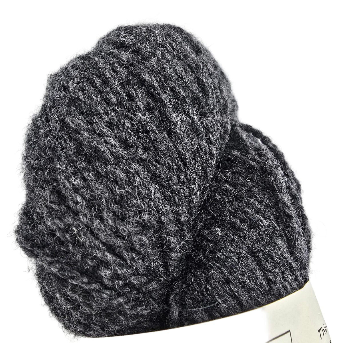 A close-up of a dark heather gray skein of yarn with a cream-colored paper label partially visible at the bottom, set against a plain white background.